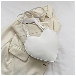 Flat lay of heart-shaped white PU leather handbag on elegant fabric background