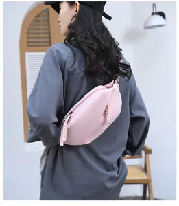 Detail of light pink crossbody chest bag showing texture and thick braided rope zippers