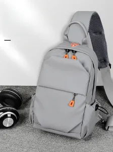 Detail of grey nylon sling bag featuring orange zipper pull and breathable mesh strap