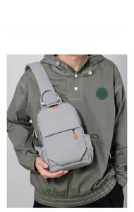 Detail of grey crossbody sling bag for men with orange zipper pulls and side drawstrings