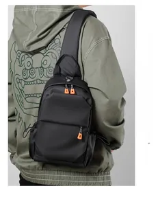 Detail of black oxford crossbody chest bag with orange zipper pulls on male model