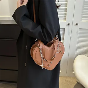 Brown heart-shaped leather crossbody bag with silver chains, rivets and cross pendant