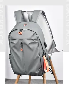 Détail du sac à dos gris avec fermetures éclair orange et port de charge USB externe