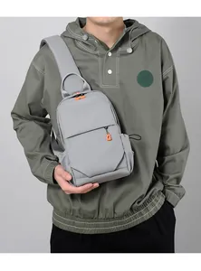 Gray minimalist shoulder bag with bright orange zipper pull shown on a male model