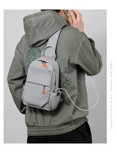 Detail of grey crossbody chest bag with USB charging port and orange zipper pulls