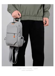 Detail of grey crossbody bag showing durable fiber fabric and orange zipper accents
