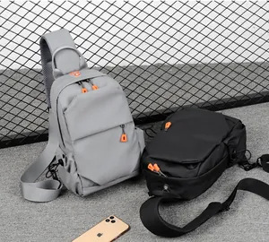 Detail of multi-pocket sling bags in black and grey with orange zipper pulls