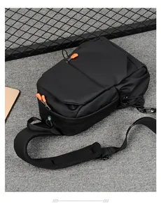 Detail of black sports chest bag with orange zipper pulls and honeycomb mesh strap