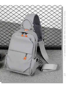 Detail of grey crossbody bag featuring orange zipper pulls and breathable mesh strap