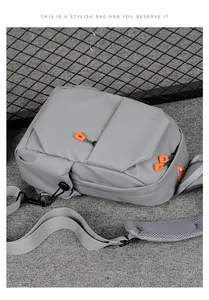 Detail of dark grey crossbody bag featuring orange zipper pulls and breathable mesh strap