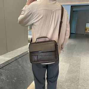 Rear view of a model wearing a brown vintage leather messenger bag with multiple zippers