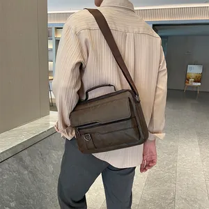 Rear view of man wearing brown leather cross body bag with multiple zipper pockets