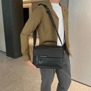 Close-up of black leather business briefcase with adjustable strap and silver D-ring