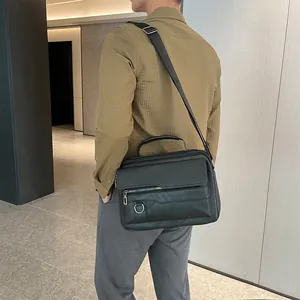 Men's black leather business crossbody bag with adjustable strap shown in use