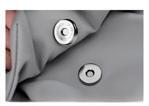 Macro shot of silver magnetic metal buckle on textured grey oxford fabric crossbody bag
