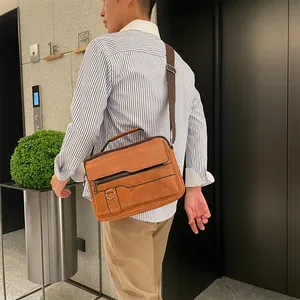 Detailed view of a vintage brown messenger bag with adjustable strap worn by a male model