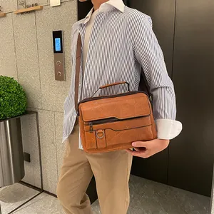 Detail of brown leather messenger bag featuring textured finish and multiple zipper pockets