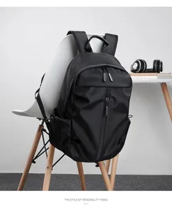 Detail of minimalist black nylon backpack with vertical zipper pocket hanging on a chair