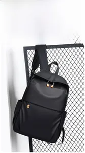 Détail du sac à dos noir mat avec fermetures éclair orange sur support grillagé