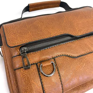 Close-up of brown textured leather briefcase featuring a zip pocket and reinforced handle