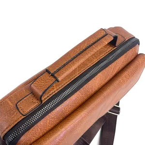 Close-up of brown textured leather briefcase featuring reinforced handles and sturdy zippers