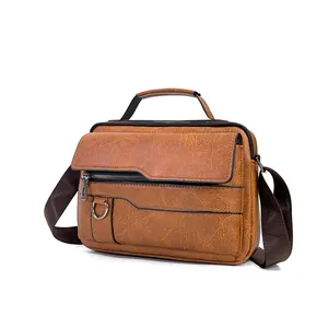 Detail of a brown leather messenger bag featuring durable handles and metal D-rings