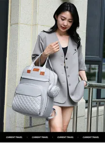 Détail du sac à dos à langer gris matelassé avec pochette latérale et étiquette en cuir