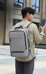 Detail view of large grey business backpack showing external USB charging port in outdoor use