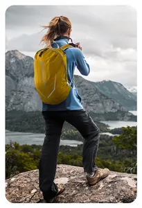 Yellow outdoor sport backpack worn by hiker on mountain peak overlooking lake