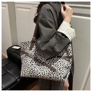 Grand sac cabas léopard avec anses en cuir marron et boucle dorée porté par un mannequin
