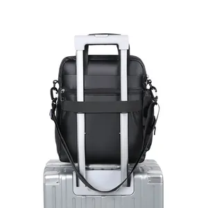Black casual sports messenger bag with back luggage strap mounted on a silver suitcase