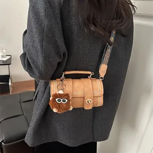 Brown retro cylindrical crossbody bag with textured jacquard strap and plush monster charm