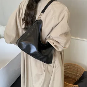 Sac à bandoulière minimaliste en similicuir noir porté par un mannequin à domicile