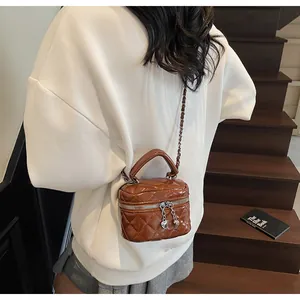 Détail du mini sac boîte marron matelassé avec bandoulière chaîne et breloque cœur