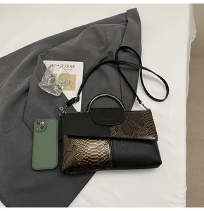 Détail d'un sac à main bicolore avec motif crocodile et poignée ronde en métal