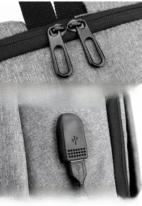 Detail of grey laptop backpack showing smooth metal double zippers and external USB charging port