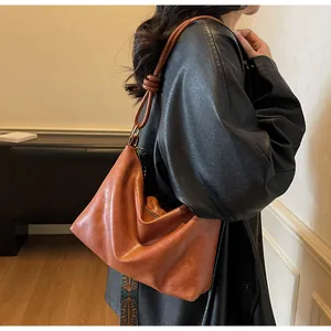 Sac à bandoulière marron en cuir avec nœuds décoratifs et plis sur un blazer noir