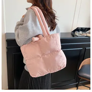 Detailed side view of the soft pink quilted crossbody bag worn by a model