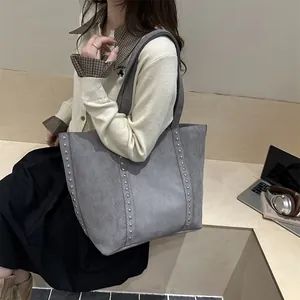 Sac fourre-tout en daim mat gris avec rivets argentés dans un décor lifestyle