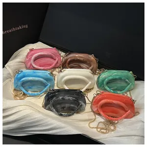 Close-up of seven assorted marble-textured acrylic shell bags with golden chains