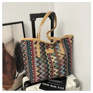 Detail einer gestrickten Bohème-Tasche mit Zickzack-Muster an einem weißen Koffer