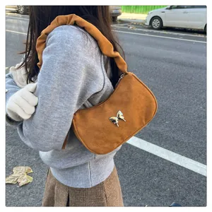 Détail du sac hobo en daim caramel avec charm papillon argenté et bandoulière froncée