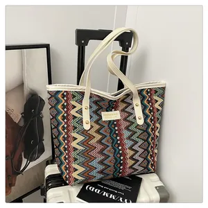 Detailaufnahme von buntem Wellenstrickgewebe und Leder-Logoetikett einer modischen Tasche