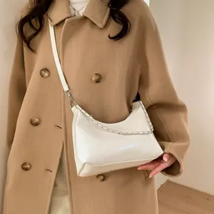 Gros plan du sac demi-lune en cuir verni blanc avec chaîne argentée et bandoulière réglable