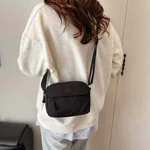 Minimalist black nylon crossbody bag with adjustable strap shown from a 45-degree angle