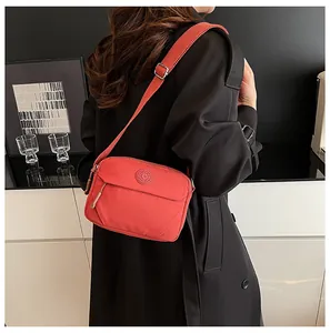 Detail of red crossbody bag with adjustable strap worn over a black winter coat