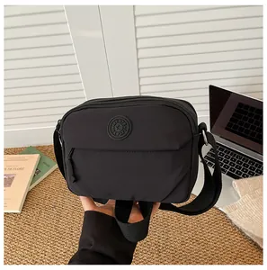 Detail of waterproof black nylon crossbody bag with front zipper and wide strap