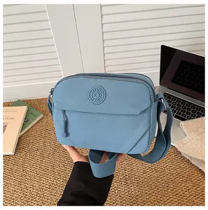 Close-up of blue nylon crossbody bag with brand logo and adjustable fabric strap detail