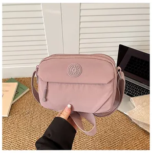 Close-up of pink nylon crossbody bag with multiple zip compartments and wide strap