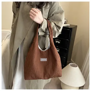 Detail of dark brown pleated tote bag featuring a stitched 'FASHION' label and fabric texture